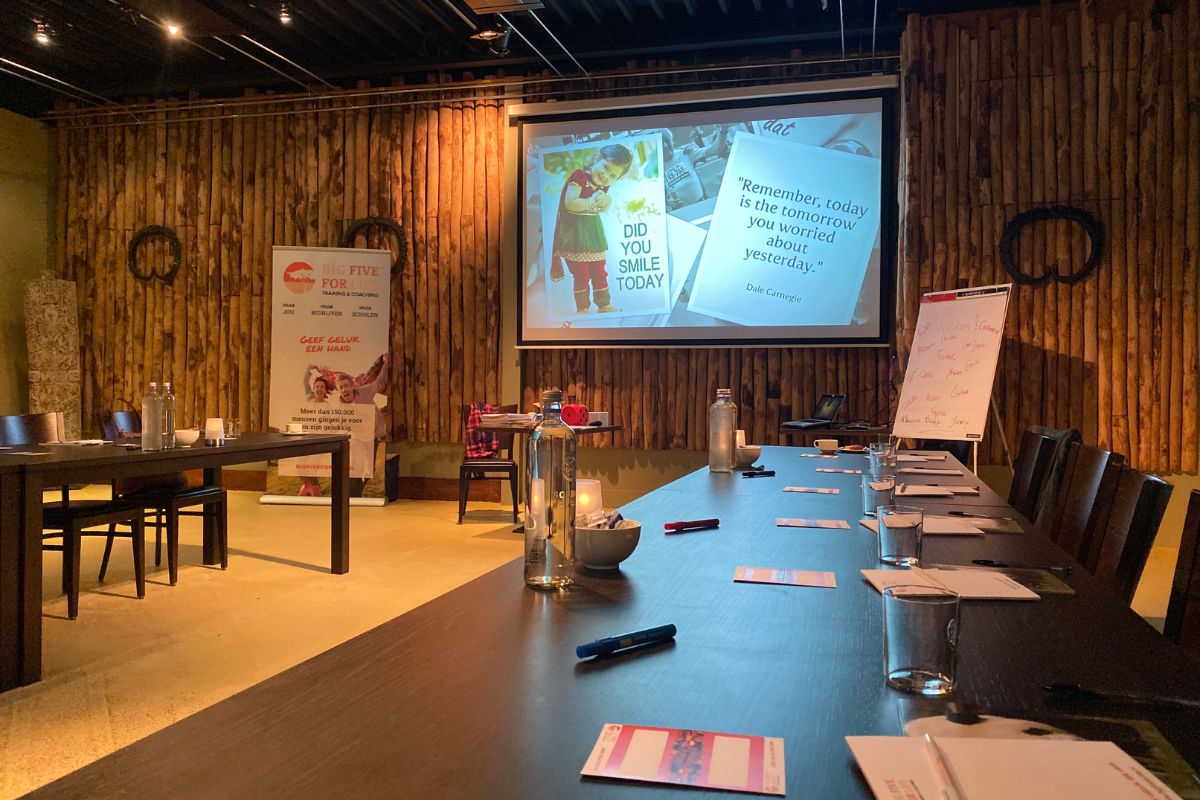 Start van een life safari workshop met een projectiescherm, stoelen, tafels en presentatiematerialen.