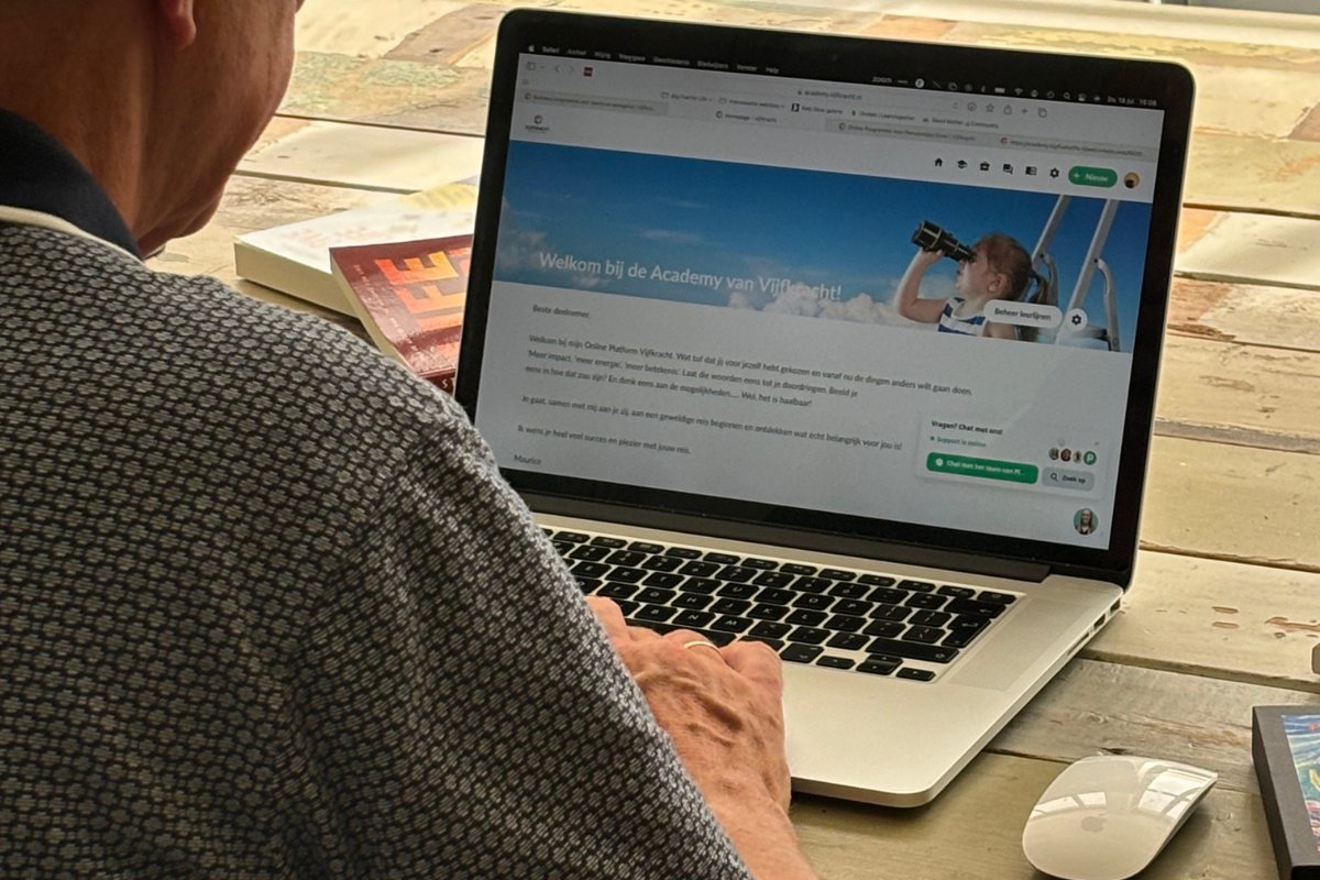 Coach Maurice van Lier kijkt naar een online platform over werkgeluk en welzijn met een titel: 'Welkom bij de Academy van Vijfkracht'. Een boek over persoonlijke ontwikkeling ligt naast de laptop.
